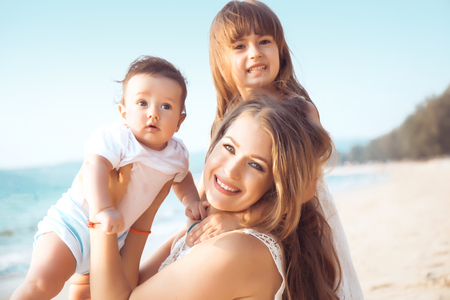 Family walking on the evening beach during sunset. Two childen with mom.の写真素材
