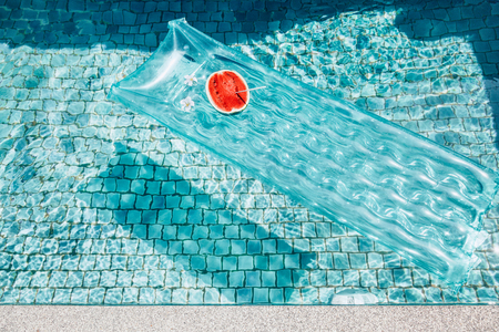 Watermelon on floating mattress in the blue pool. Tropical fruit diet. Summer holiday idyllic.の写真素材