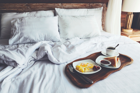 Brekfast on a tray in bed in hotel, white linen, wooden intreior