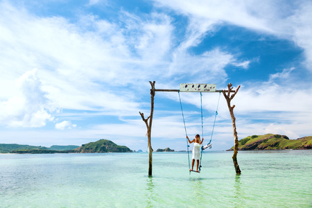 Woman swinging at tropical beach, sunny day, good weather. Swinging in paradise island.の写真素材
