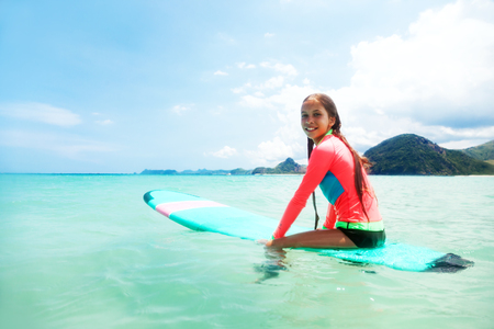 Kid girl is learning surfing, riding a waveの写真素材
