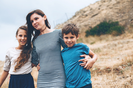 Mom with two preteen children walking outdoor, cool autumn weatherの写真素材