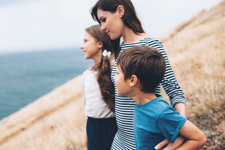 Mom with two preteen children walking outdoor, cool autumn weatherの写真素材