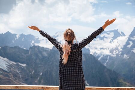Woman relaxing on terrace on mountain, alpine view, snow on hills. Dombay, Karachay-Cherkessia, Caucasus, Russia.の写真素材