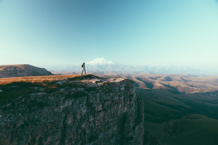 Traveler standing on top of Bermamyt plateau and looking on Elbrus mountain. Karachay-Cherkessia, Caucasus, Russia.の写真素材