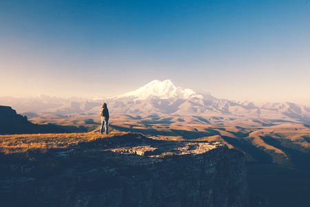 Traveler standing on top of Bermamyt plateau and looking on Elbrus mountain. Karachay-Cherkessia, Caucasus, Russia.の写真素材