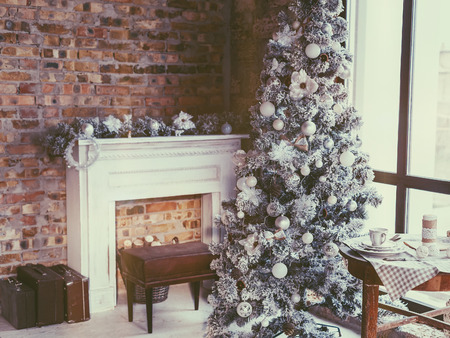 Winter home decor. Christmas tree in loft interior against brick wall. Old vintage furniture.の写真素材