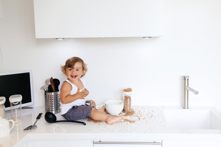 1,4 years old child playing with food ingredients and utensils alone in the white kitchen tableの写真素材
