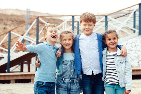 Group of fashion children wearing denim clothing having fun on the sea shore. Autumn casual outfit in blue and navy color. 7-8 years old models.の写真素材