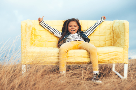 7 years old child sitting on a sofa in the autumn field outdoor.の写真素材