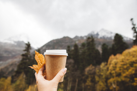 Drinking take away coffee in mountains. Fall trip. Rain weather. Freedom travel concept. Autumn...