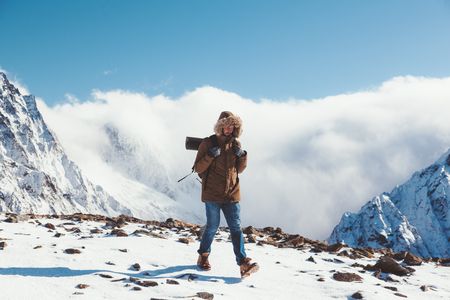 Man with backpack trekking in mountains. Cold weather, snow on hills. Winter hiking.の写真素材