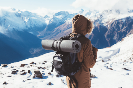 Man with backpack trekking in mountains. Cold weather, snow on hills. Winter hiking.の写真素材