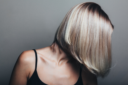 Model with unrecognizable face with blond shiny hair. Woman bob haircut styling.