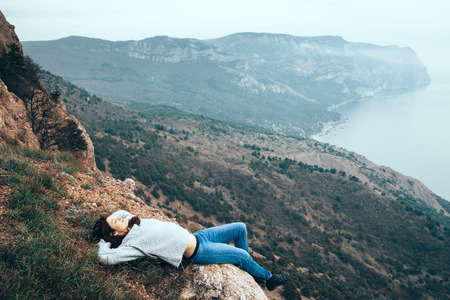 Girl travel in mountains alone. Spring weather, calm scene. Backpacker walking outdoors, back view over landscape. Wanderlust photo series.の写真素材
