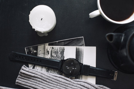 Winter cozy concept. Flatlay of gray knitted sweater, candle and coffee drink on black iron table. Warm weekend in cold weather.の写真素材