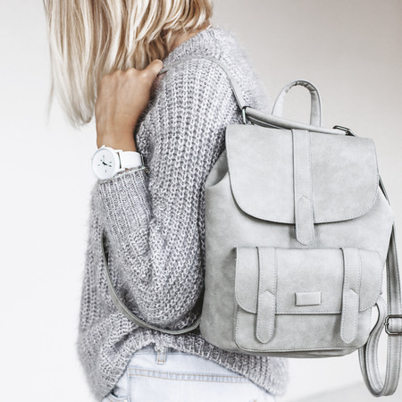 Unrecognizable model wearing casual outfit and holding leather backpack. Gray clothing in trendy minimalistic style. Street fashion for spring or fall season. Details of everyday elegant look.の写真素材