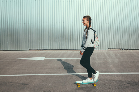 11-12 years old tween girl wearing fashion sportswear rollerskating on skateboard in the city street, urban hipster styleの写真素材
