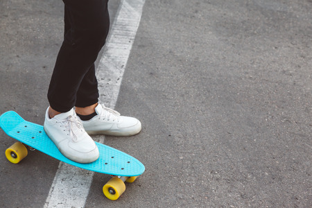 Girl wearing fashion sportswear rollerskating on skateboard in the city street, urban hipster style, feet in shoes closeupの写真素材