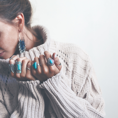 Boho jewelry on model: ethnic stone rings and earrings. Beautiful woman wearing warm woolen sweater and fashion jewellery. Minimal style and pastel tone.の写真素材