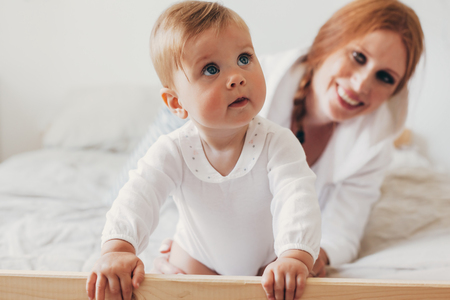 Portrait of loving mom playing with her 8 months old baby in bedroomの写真素材