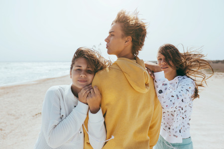 Group of teenage friends having fun on the beach. Hipster boy and girls playing outdoors.の写真素材