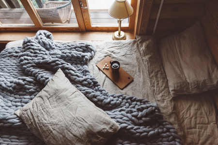 Rustic interior decoration of log cabin bedroom. Cozy warm blanket on bed by window, top view from above.の写真素材