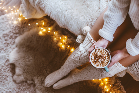 Cold autumn or winter weekend while drinking warm cocoa with marshmellows. Lazy day in knitted socks on the couch. Cosy scene, hygge concept, top veiw.の写真素材