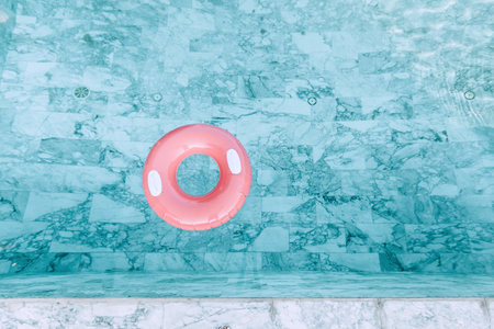 Pink pool float in blue water. Photo of inflatable ring from above.