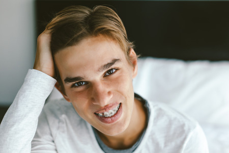 Bright closeup portrait of a 16 years old teenage guy wearing dental bracesの写真素材