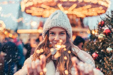 Girl walking in Christmas market decorated with holiday lights in the evening. Feeling happy in big city. Spending winter vacations in Red square, Moscow, Russia.の写真素材