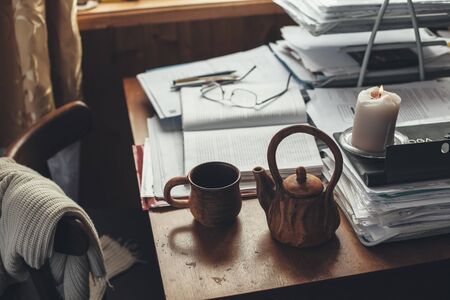Cozy home office in wooden house. Drinking tea while working with papers.の写真素材