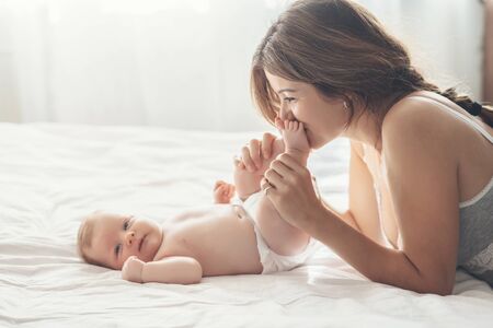 Loving mom carying of her newborn baby at home. Mother kissing her little 2 months old son.の写真素材