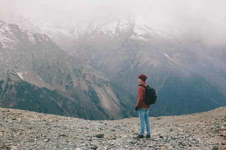 Young backpacker standing on mountain. Cold weather, snow on hills. Winter hiking scene.の写真素材