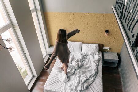 Young teen girl relaxing on comfy bed in modern hotel room, top viewの写真素材