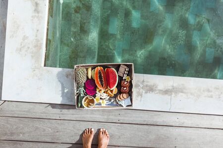 Served tray with fruit plate by hotel pool on Bali villa. Exotic summer diet. Tropical beach...