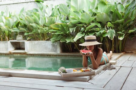 Girl relaxing and eating fruits in the pool on luxury villa in Bali. Exotic summer diet. Tropical beach lifestyle.の写真素材