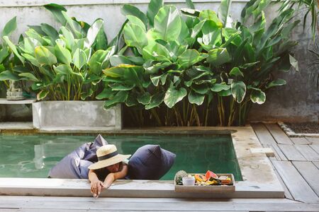Girl relaxing and eating fruits in the pool on luxury villa in Bali. Exotic summer diet. Tropical beach lifestyle.の写真素材
