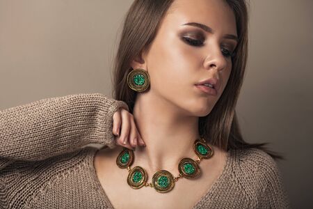 Fashion portrait of young beautiful girl with perfect smokey makeup wearing vintage jewelry. Teen model with elegant jewelery on brown background.の写真素材