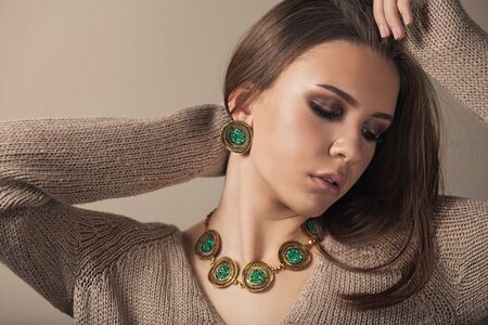 Fashion portrait of young beautiful girl with perfect smokey makeup wearing vintage jewelry. Teen model with elegant jewelery on brown background.の写真素材