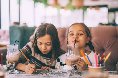 Children drink smoothie in family cafe. Two little friends celebrating birthday party in indoor restaurant.の写真素材