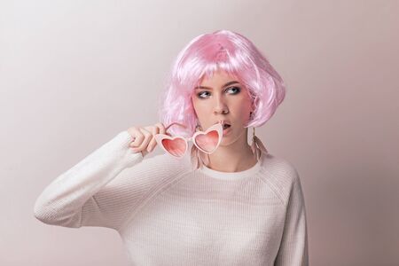 Portrait of teenage model with pink hair posing against pastel background. Studio photo of funky teenager wearing color wig and trendy glasses.の写真素材