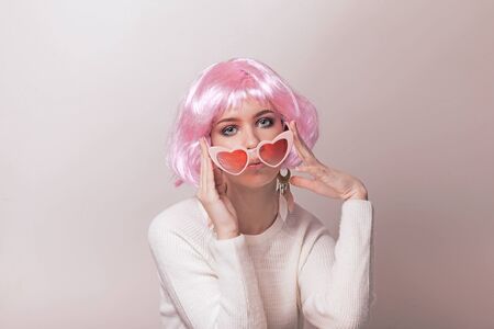 Portrait of teenage model with pink hair posing against pastel background. Studio photo of funky teenager wearing color wig and trendy glasses.の写真素材