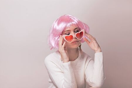 Portrait of teenage model with pink hair posing against pastel background. Studio photo of hipster teenager wearing color wig and trendy glasses.の写真素材