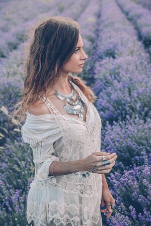 Beautiful model walking in spring or summer lavender field. Boho style clothing and silver jewelry.の写真素材