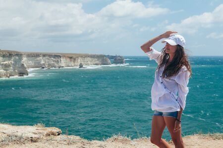 Back view of young traveller enjoying summer breeze while viewing beautiful sea landscapeの写真素材