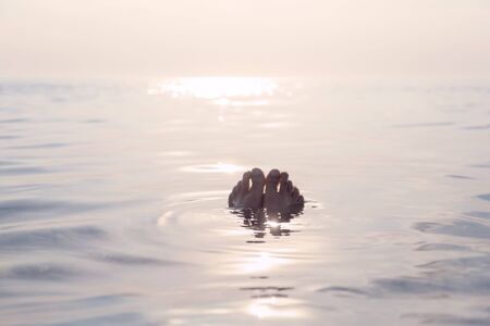 Floating med feet in serene sea water in sunset. Relax and quet idyllic summer concept.
