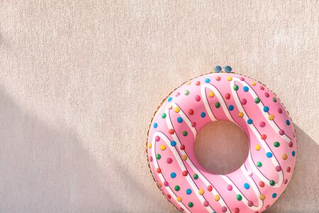 Inflatable donut and glasses against pink wall in summer sunny day, beach vacation concept scene.の写真素材