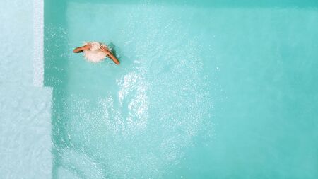 Woman in straw hat relaxing in clear pool water in hot sunny day on Bali villa. Summer holiday...