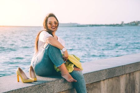 Carefree and happy plus size woman taking off her shoes, relaxing and enjoing sun light while walking on city streetの写真素材